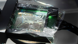 Closeup of a liquid on a glass plate, which is lit from below. Cables extend from the plate, and are held together by a braid.