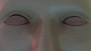 A grid of uncanny off-kilter faces generated with 3D software. Each face is centered in a tile with varying facial features and skin tones. All of the faces are bald with sharp lighting.